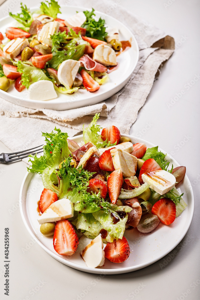 Vertical shot salads with jamon, strawberries, grapes, mozzarella and olives with pomegranate sauce. Healthy and balanced nutrition. Organic food. Mediterranean cuisine recipes. Copy space Vertical shot salads with jamon, strawberries, grapes, mozzarella and olives with pomegranate sauce. Healthy and balanced nutrition. Organic food. Mediterranean cuisine recipes. Copy space