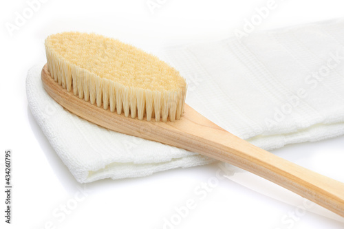 A dry massage brush made of natural materials and a cotton towel on a white background. Cleanliness and body care concept