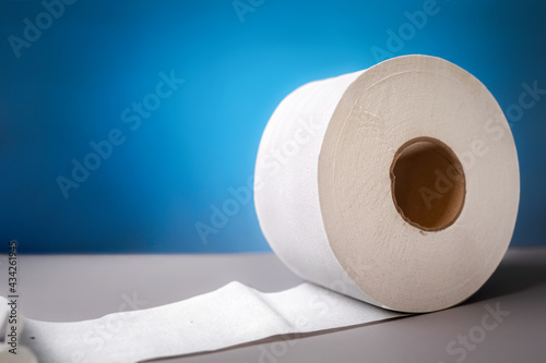 A roll of toilet paper on blue background close-up. The concept of panic purchasing of essential goods. Coronovirus, pandemic, hygiene. Copy space