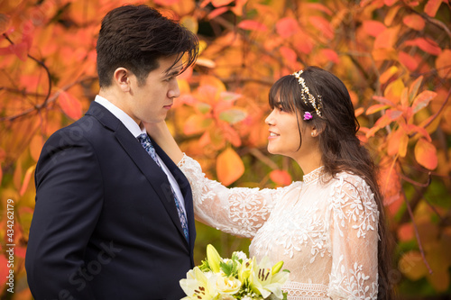 Bride and groom outdoors in autumn with orange fall leaves