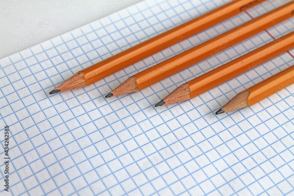 pencils lie on a notebook sheet in a cage pencils lie on a notebook sheet in a cage