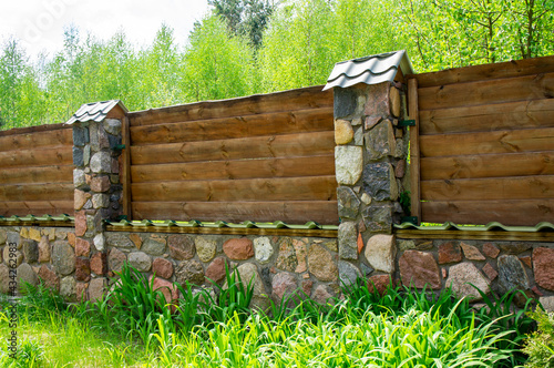 Old vintage wooden rustic fence with stone foundation