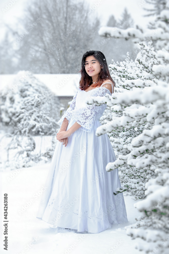 Biracial teen girl with white dress outside in snow