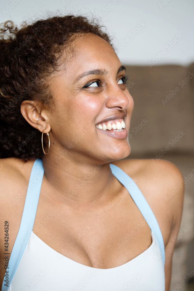 Multiethnic woman with dark skin looking to the side and smiling