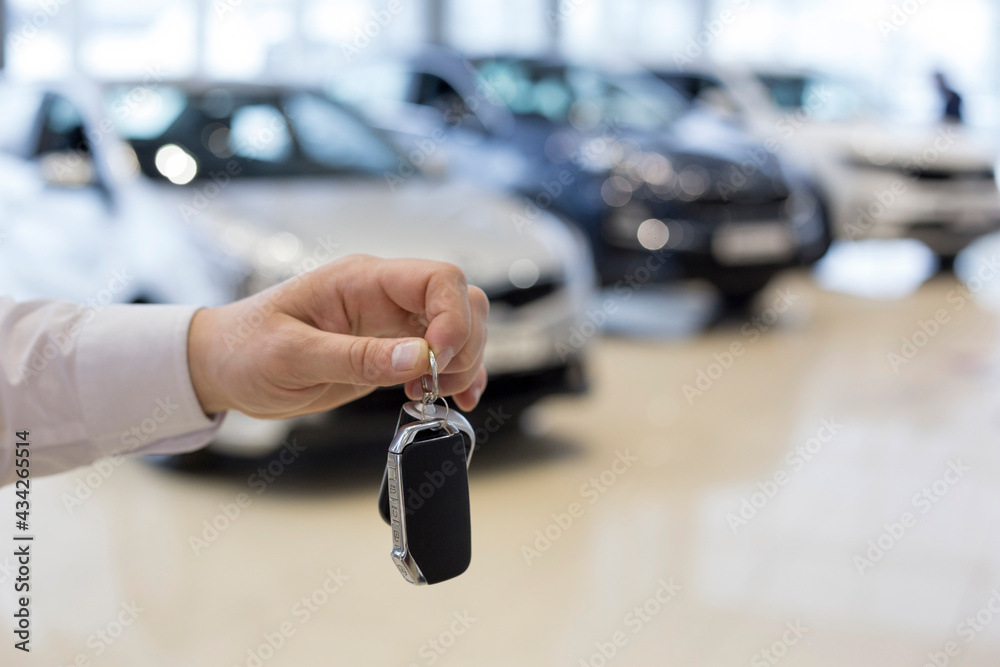 Salesman holding keys to a new car. Car auto dealership.