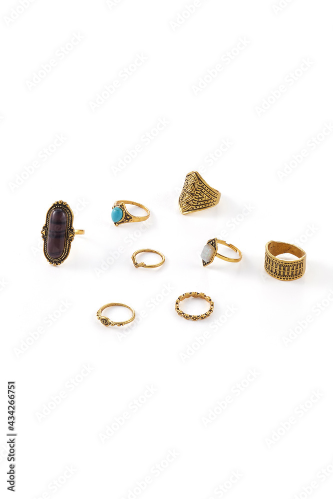Close-up shot of eight bronze rings with figured carving. Three rings are decorated with brown, turquoise and nacre ornamental stones. Jewelry set in ethnic style is isolated on the white background. Close-up shot of eight bronze rings with figured carving. Three rings are decorated with brown, turquoise and nacre ornamental stones. Jewelry set in ethnic style is isolated on the white background.