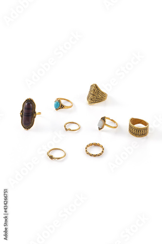 Close-up shot of eight bronze rings with figured carving. Three rings are decorated with brown, turquoise and nacre ornamental stones. Jewelry set in ethnic style is isolated on the white background. 