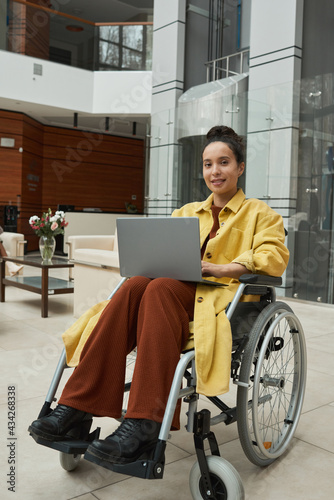 Portrait of young disabled businesswoman in wheelchair using laptop computer