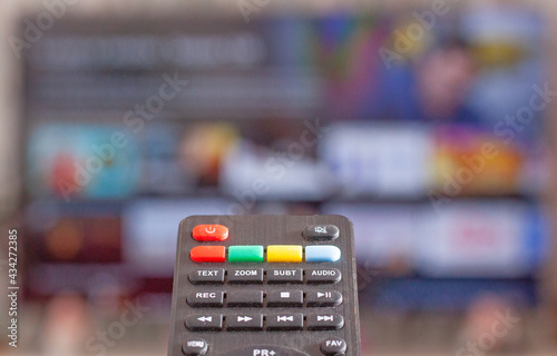 Vista de un mando a distancia señalando a un televisor con una aplicación de cine y series