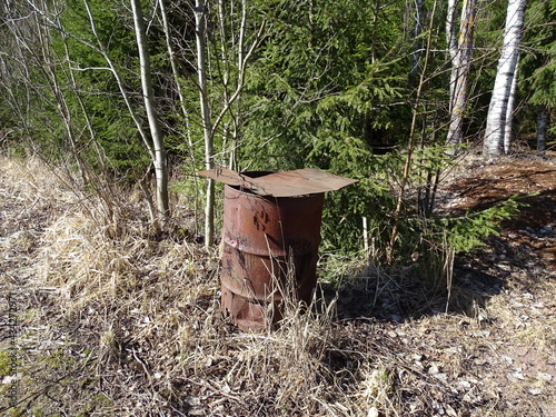 Rusty iron barrel on the edge of the forest