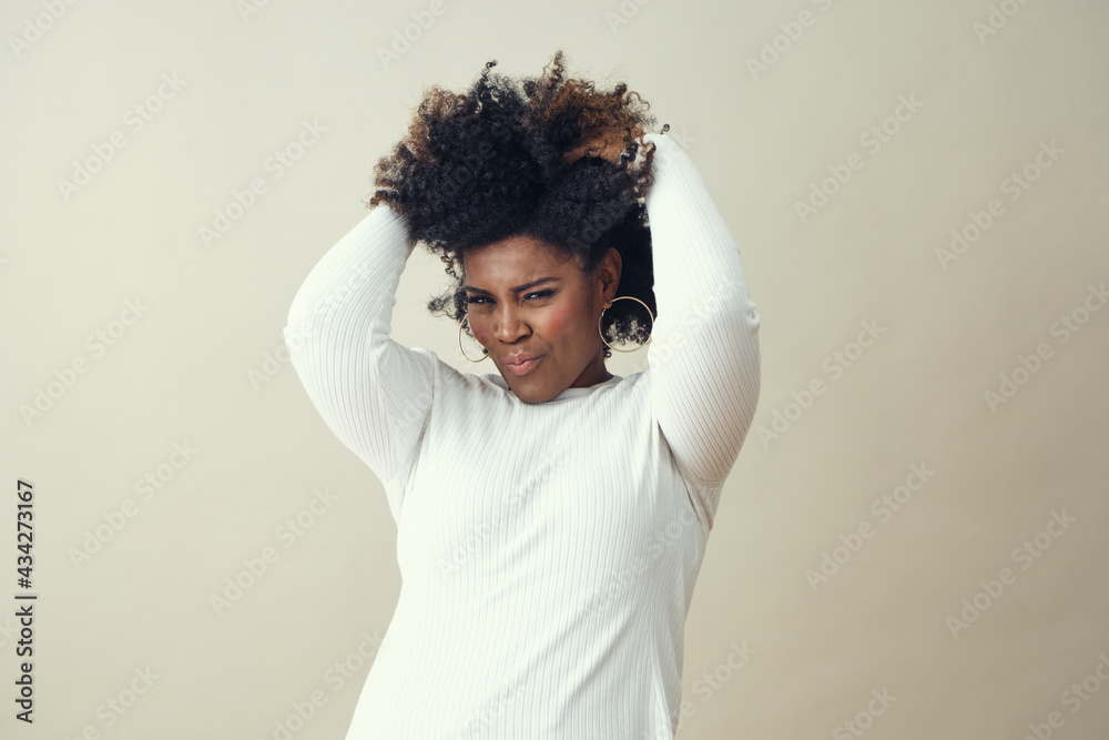 African American woman in her 30's with hands In hair in a fashion pose African American woman in her 30's with hands In hair in a fashion pose