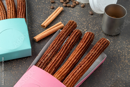 Top view of take away coffee next to chocolate filled and plain churros.