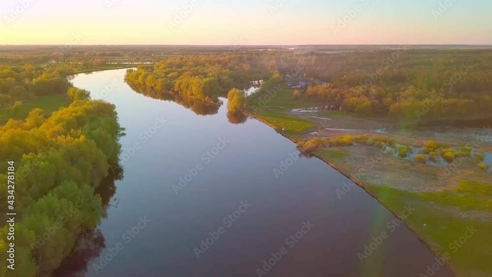 Beautiful view of the Picturesque Winding River surrounded by Forest at sunset. Aerial Drone Shot. In the background, flood meadows from the flood of the Dnieper River. Belarus