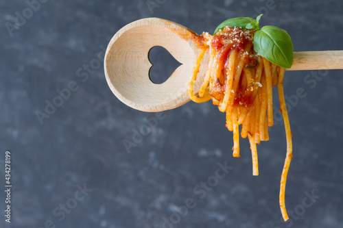 Spaghetti on spoon with heart, dark background, love italian food concept