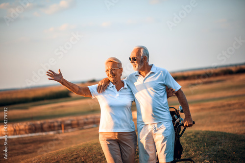 Billede på lærred Senior golfers on golf course.  Woman waving to somebody.