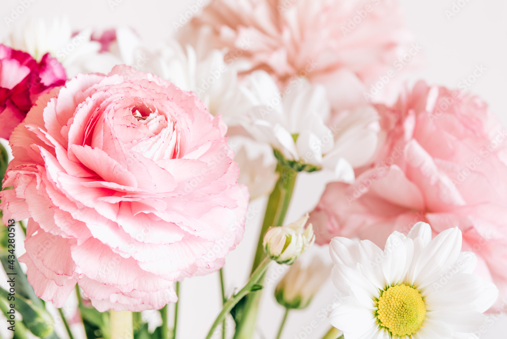 A bouquet of fresh spring flowers in a glass vase on a white table.