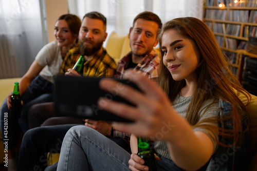 Friends hanging out together on a house party taking selfie with a smartphone and drinking beer