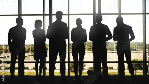 Canvas Print Full length back view backlit shot with silhouettes of six people, men and women