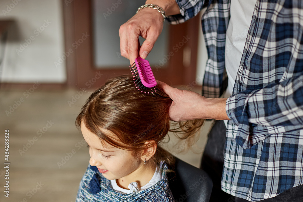 Fototapeta premium Father combing, brushing his daughter's hair at home
