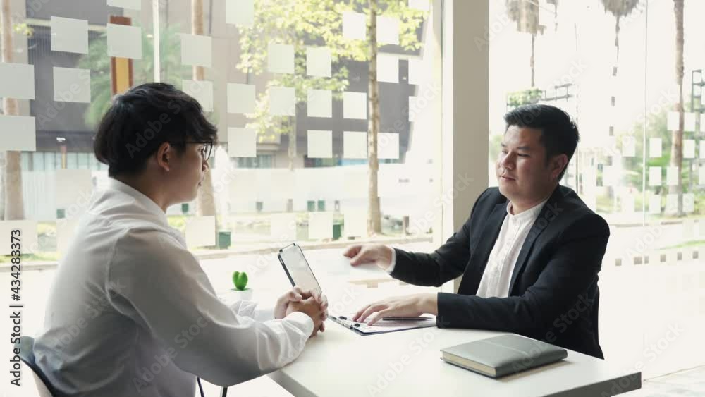 Male manager is talking or explaining about having to dismiss the employee while being handed out a resignation envelope to the employee. Male manager is talking or explaining about having to dismiss the employee while being handed out a resignation envelope to the employee.