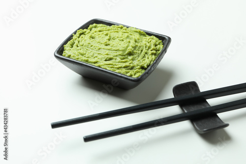 Chopsticks and wasabi sauce on white background