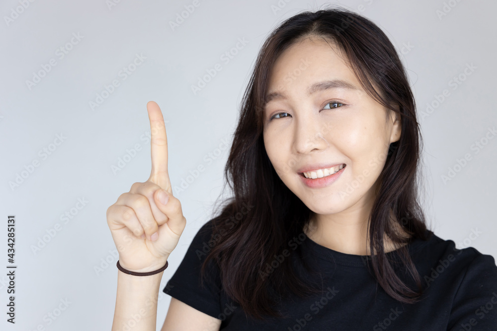 asian woman pointing one finger, portrait of positive happy smiling asian woman pointing up one finger for first winner concept asian woman pointing one finger, portrait of positive happy smiling asian woman pointing up one finger for first winner concept