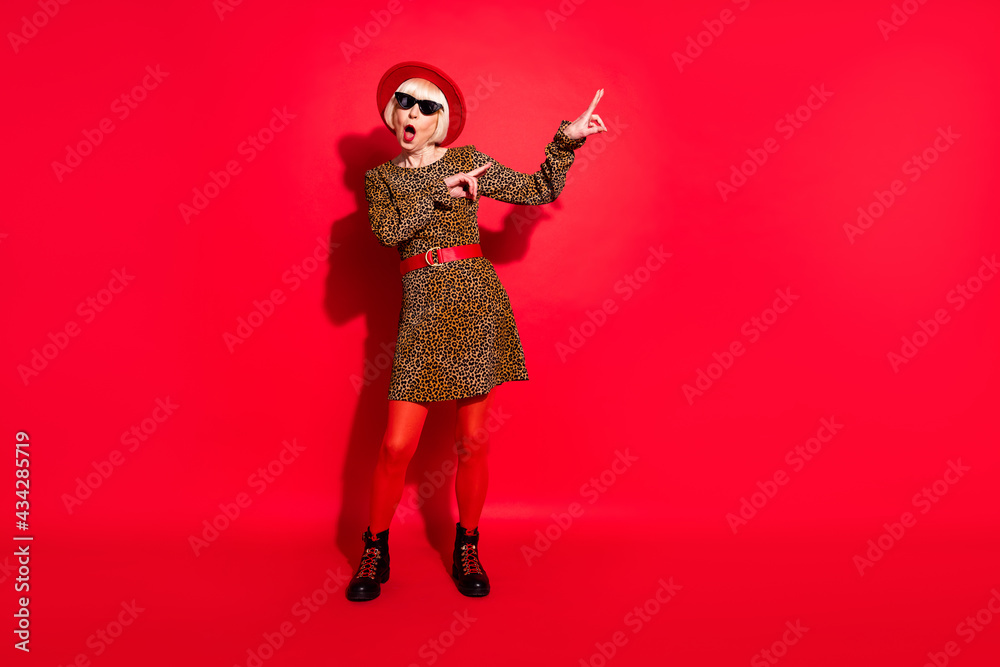Full length photo of shocked amazed old woman dance good mood point finger isolated on red color background Full length photo of shocked amazed old woman dance good mood point finger isolated on red color background