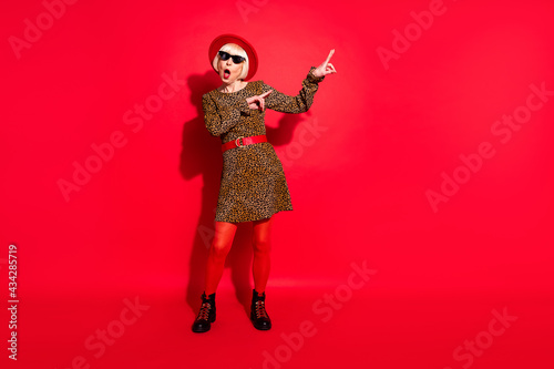 Full length photo of shocked amazed old woman dance good mood point finger isolated on red color background