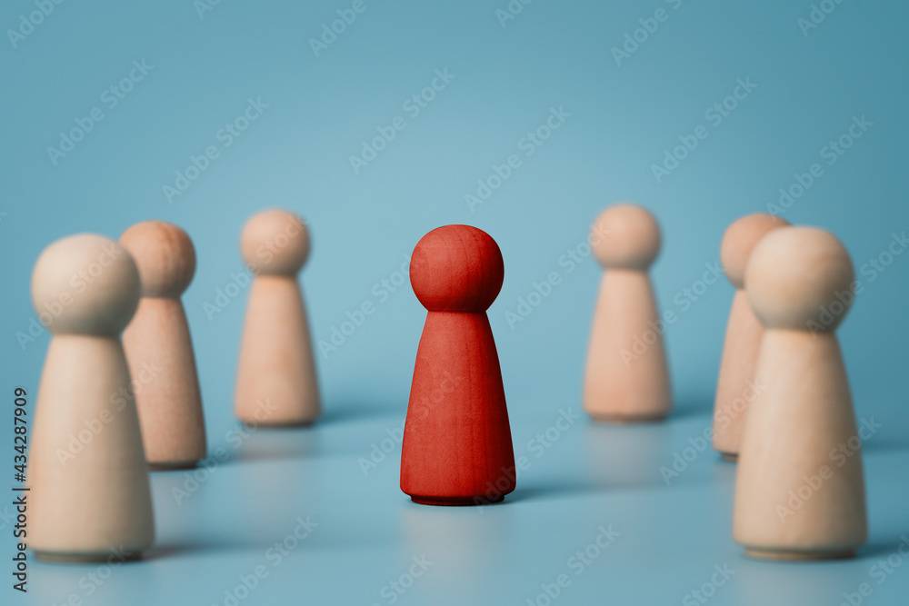 Red wooden figure standing on centre among normal other wooden figure , Leadership different thinking idea and disruption concept. Red wooden figure standing on centre among normal other wooden figure , Leadership different thinking idea and disruption concept.