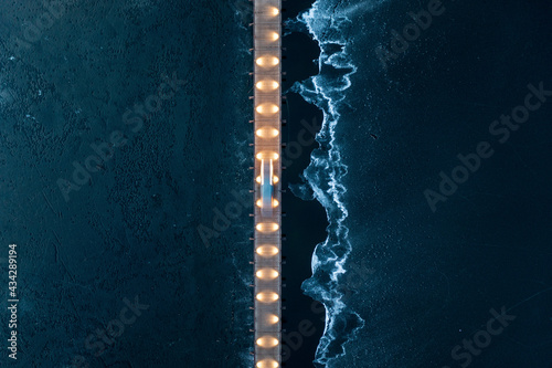 Aerial view of vehicle driving on illuminated bridge over the frozen lake in Trakai, Lithuania.