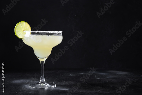 Classic Margarita or Daiquiry cocktail with lime and ice isolated on dark black background with copy space. photo