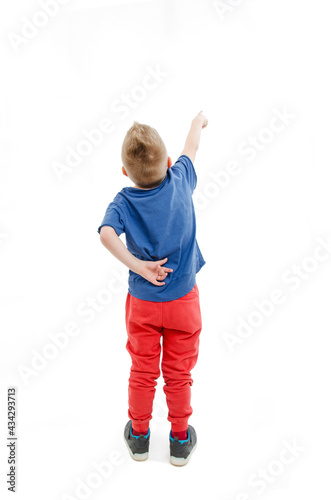 Back view of little boy points at wall. Rear view. Isolated on white background
