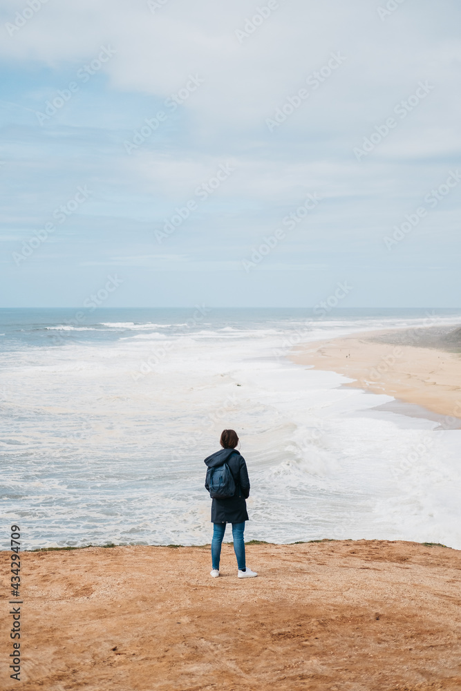 A lonely woman overlooking a beach in Nazare, Portugal