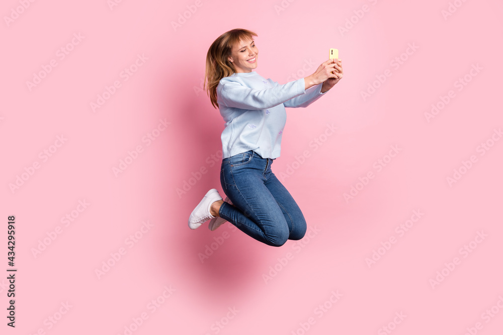 Full length body size view of pretty cheerful girl jumping using device browsing app 5g isolated over pink pastel color background