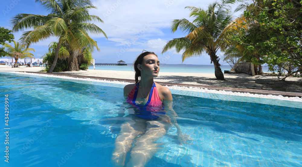 girl in a bikini by a palm tree in a tropical resort