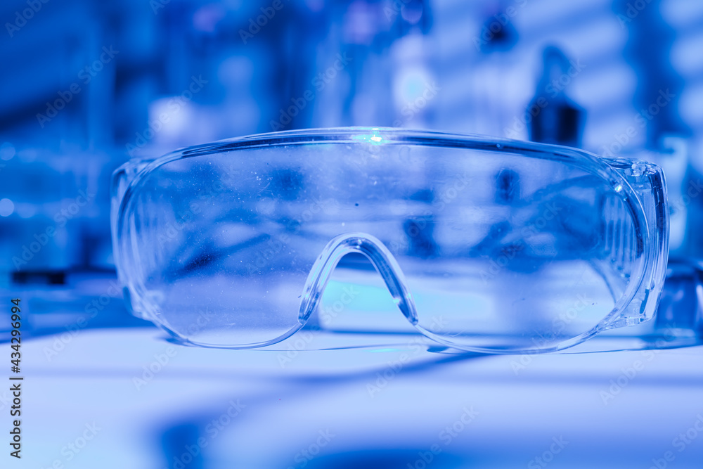Protective glasses of scientist researcher on a laboratory table, with blue light environment Protective glasses of scientist researcher on a laboratory table, with blue light environment