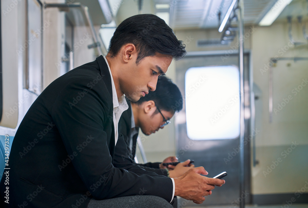 Two businessman use mobile phone in underground train for go home