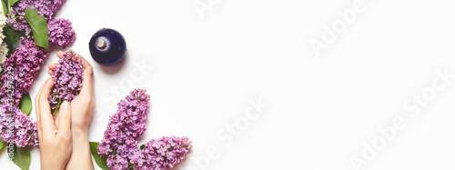 perfumery and flower aroma concept. femalehands hold a branch of lilac on a white background. perfume with lilac scent. copy space. banner