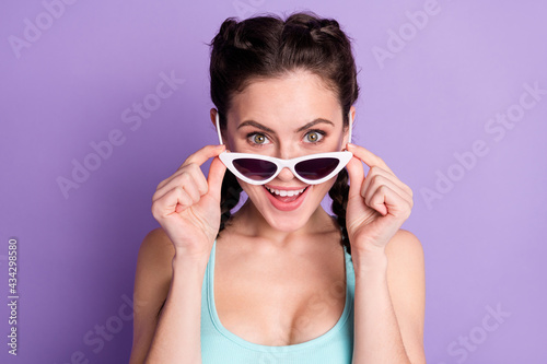 Photo portrait of young woman smiling amazed wearing sunglass isolated on pastel violet color background
