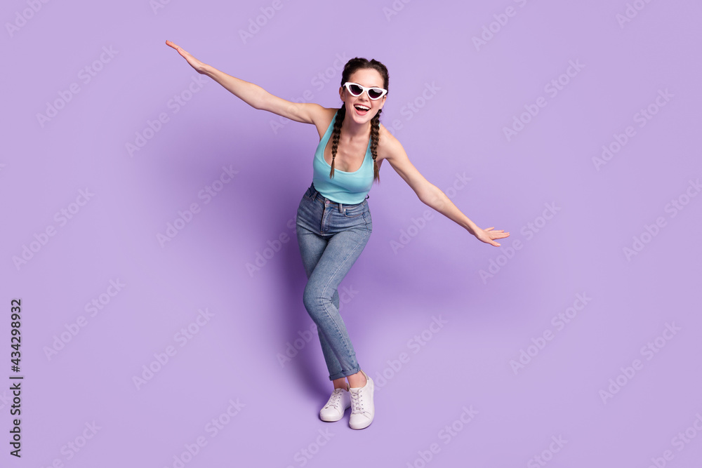 Full length body size view of attractive cheerful childish girl having fun flying like plane isolated over violet purple color background
