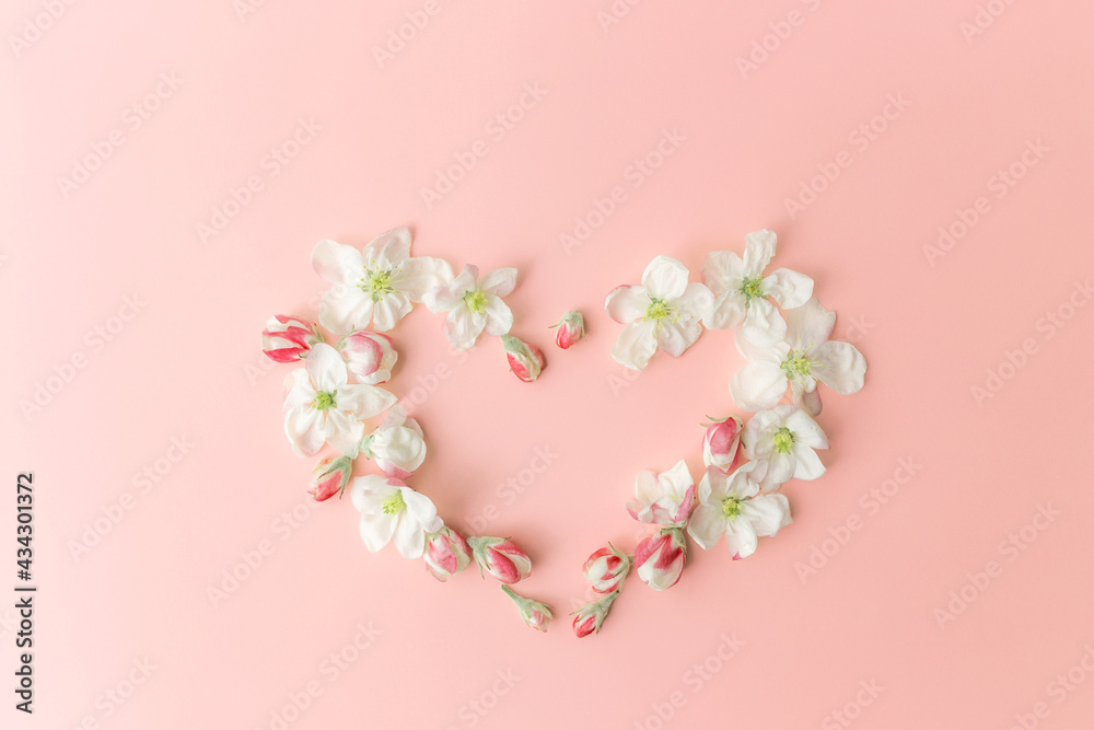 Flat lay on pink background with apple blossom heart shape ornament border
