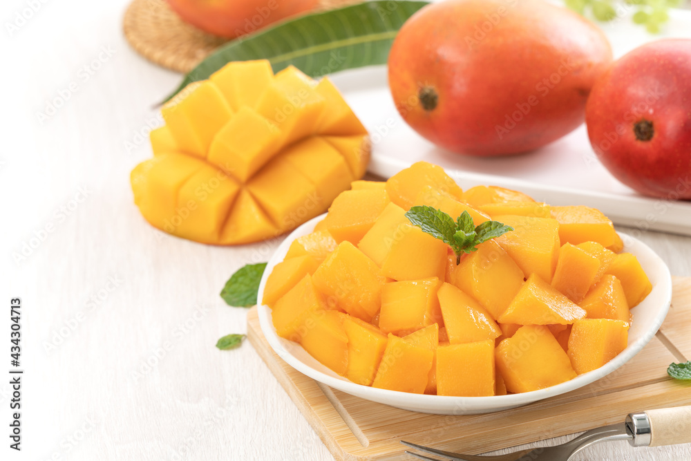 Diced fresh mango fruit on a white plate with leaves. Diced fresh mango fruit on a white plate with leaves.