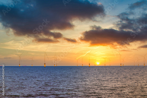 Offshore Wind Turbine in a Windfarm under construction off the England Coast at sunset © nuttawutnuy