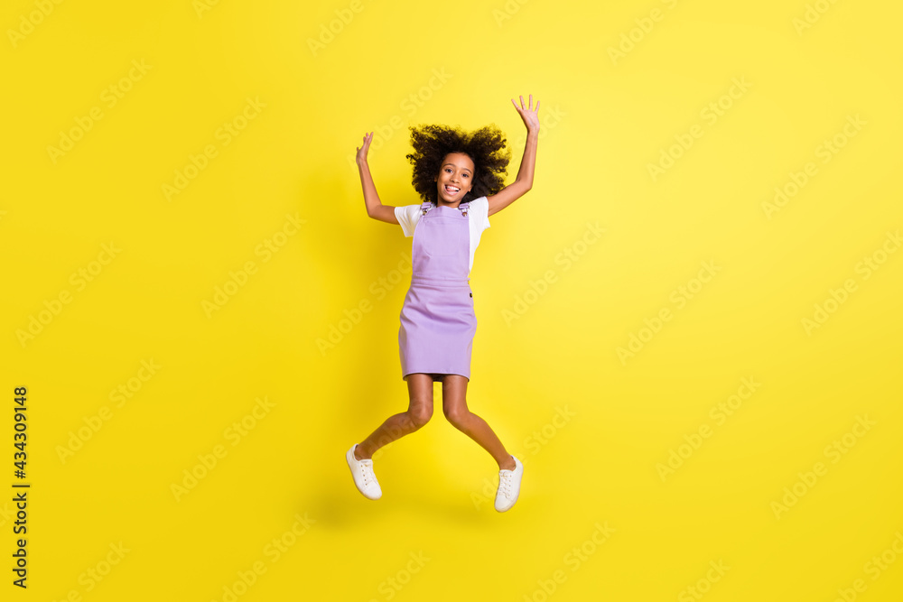Full length body size view of cheerful childish wavy-haired girl jumping fooling having fun isolated over bright yellow color background