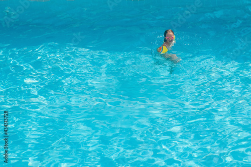 Pretty little girl in the pool at the resort. Summer holiday and happy carefree childhood concept. Copy space for design or text.