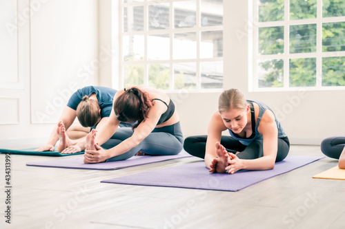 Diversity group of people do yoga workout together. Asian and Caucasian group do yoga leg stretching