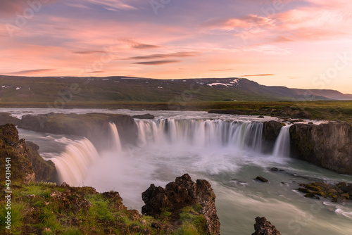 Majestic waterfall under a dramatic sky lit by midnight sun in summer. Godafoss waterfall, Iceland.
