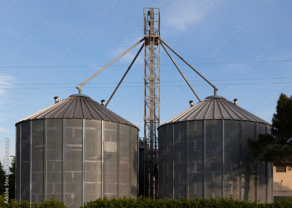 Two metallic silos on a rural background