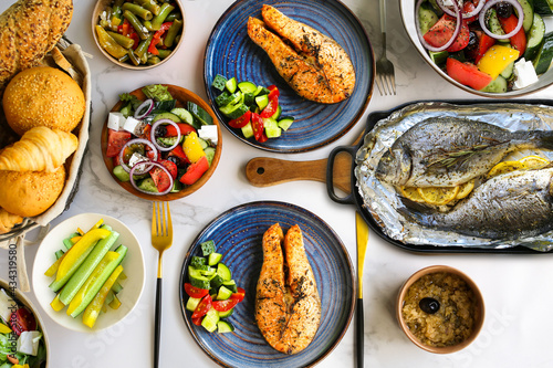 Mediterranean cuisine on the table.Dorada from the oven with salad and vegetables.Salmon with salad.Proper nutrition on the table.Vegetables with baked fish.Finished fish.Dorado grill.Greek salad.