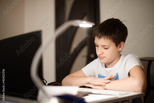 Schoolboy studies at home during coronavirus pandemic lockdown. Distance learning online education.